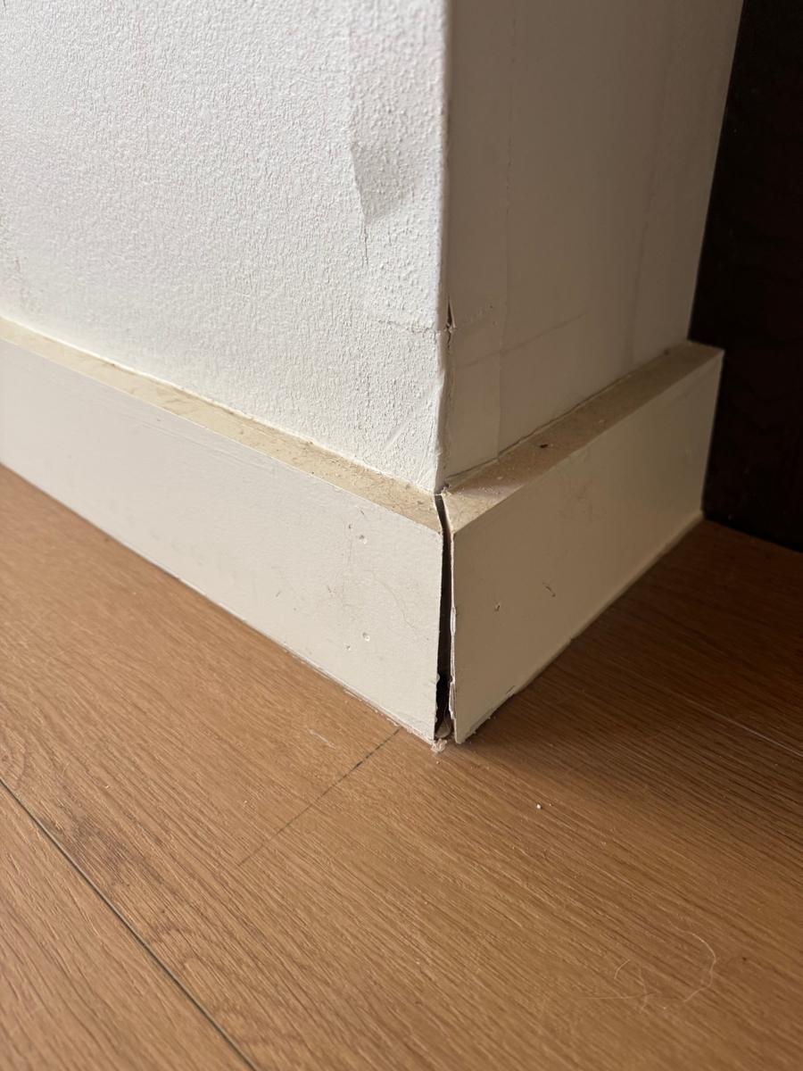 Baseboard corner pulled apart with a visible gap