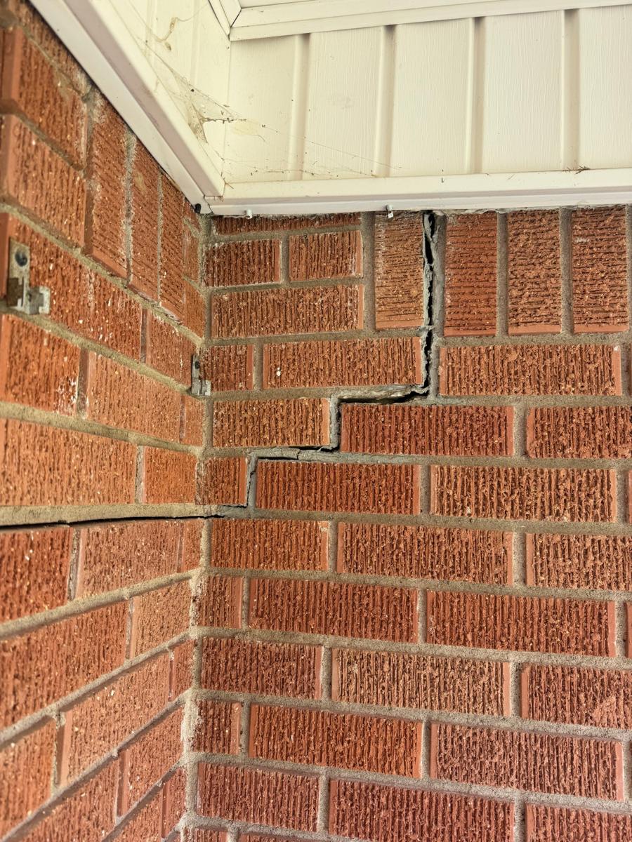 Stair-step crack running through brick mortar under an eave